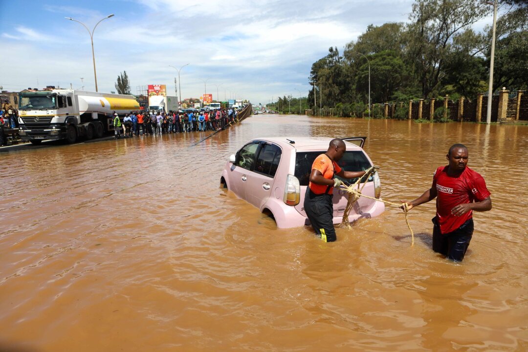 Bereits 257 Flutopfer in Kenia - Menschen in Nairobi, die im Hochwasser ein Auto ziehen.