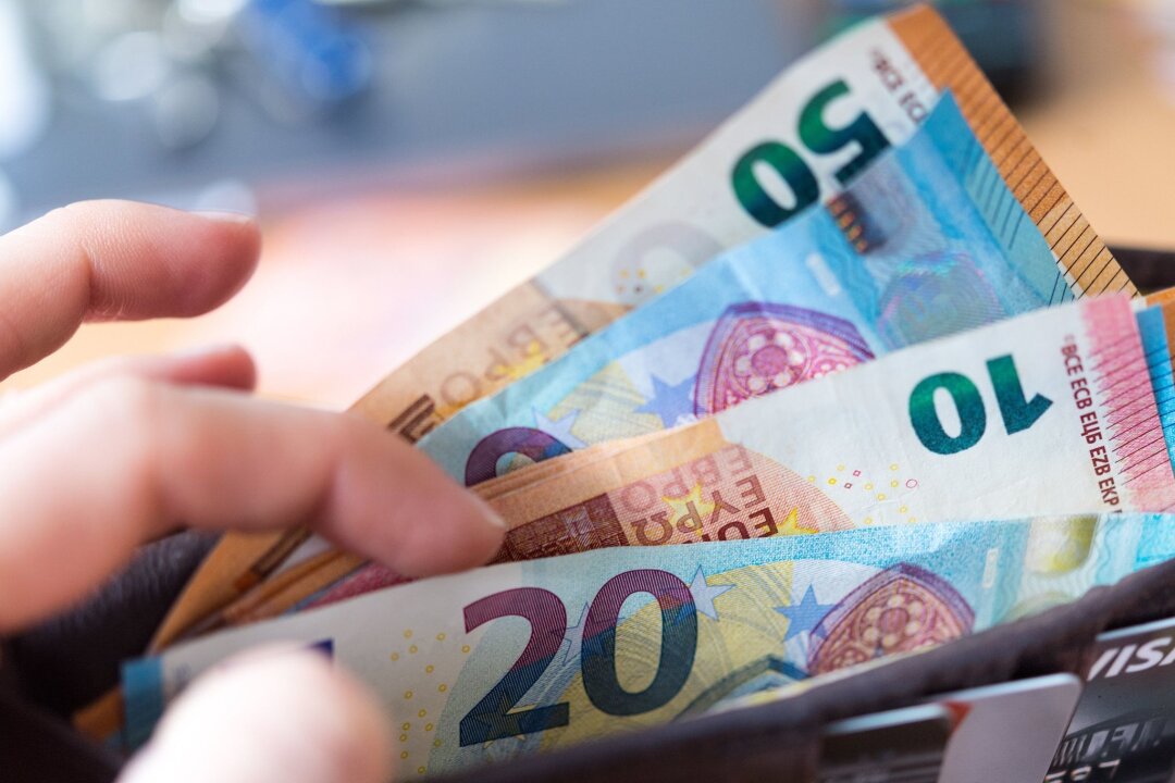 Inflation bleibt in Sachsen unter drei Prozent - Eine Frau hält eine Geldbörse mit Banknoten in der Hand.
