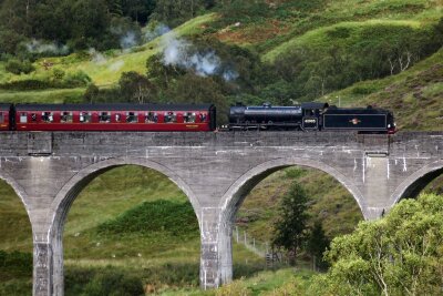 7 bekannte Drehorte, die man im Urlaub besuchen kann - Vielleicht winkt gleich Harry Potter? Der Touristenzug Jacobite Steam Train fährt über das Glennfinnan-Viadukt, das Harry-Potter-Fans aus den Filmen kennen.