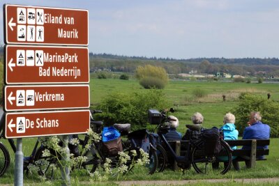 Äpfel statt Tulpen: Im Obstgarten der Niederlande - In der Betuwe gibt es ein dichtes Netz von Radrouten: Hier machen bei Eck en Wiel nahe Buren Radreisende Pause am Nederrijn (Niederrhein).