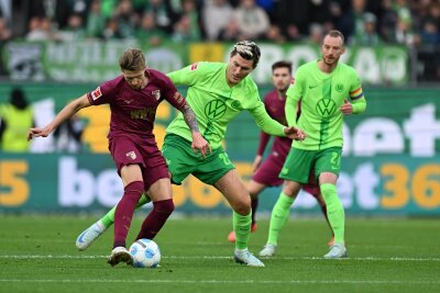 Amoura bewahrt Wolfsburg vor Niederlage gegen Augsburg - Augsburgs Kristijan Jakic (l) spielt gegen Wolfsburgs Jonas Wind.