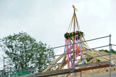 Anfänger am Werk: So wird Ihr Bau kein Luftschloss - Richtkranz auf einem neu gebautem Haus. Richtfest auf einer Lückenbebauung. An einem neu gebauten Wohnhaus im Speckgürtel von Leipzig hängt ein Richtkranz im rohbaufertigen Dachstuhl.