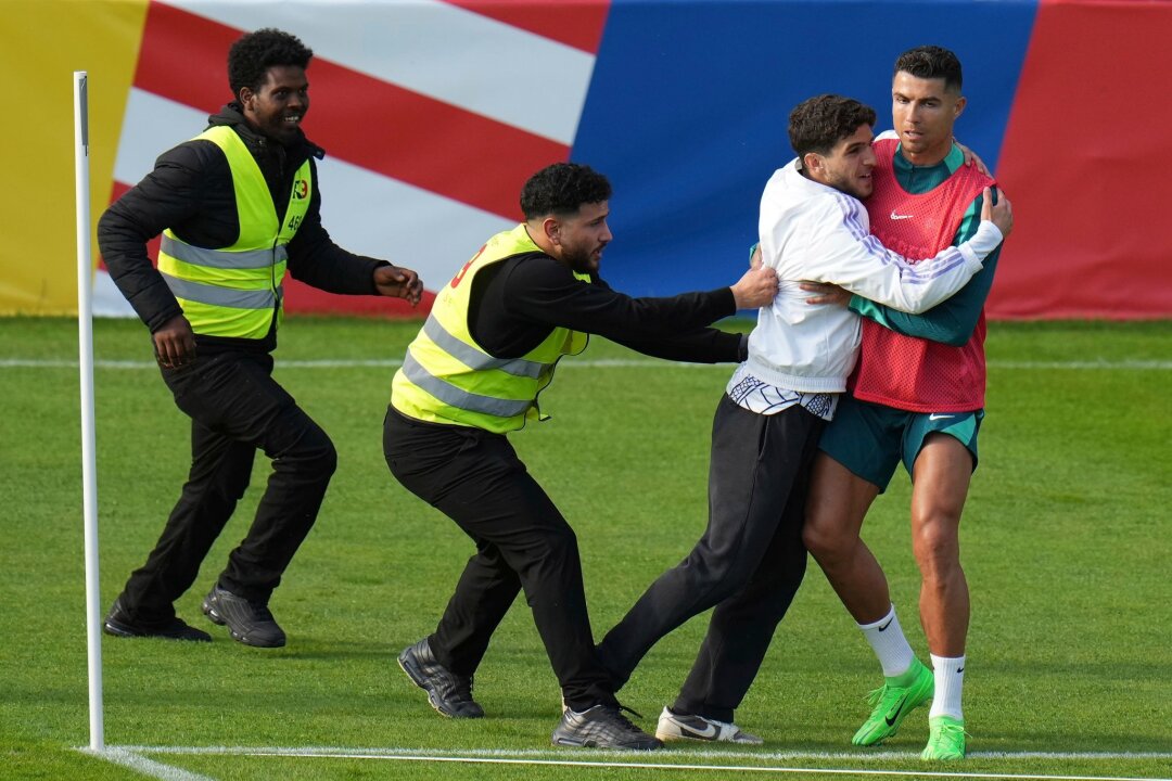 Auch Mitspieler staunen über Ronaldo-Effekt - Ein Fan sprintet in Gütersloh auf den Trainingsplatz und umarmt Portugals Superstar Cristiano Ronaldo.