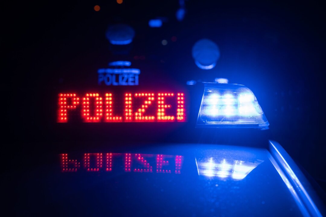 Betrunkener attackiert Fahrzeuginsassen in Leipzig - Zwei Einsatzkräfte stehen vor einem Polizeiwagen.