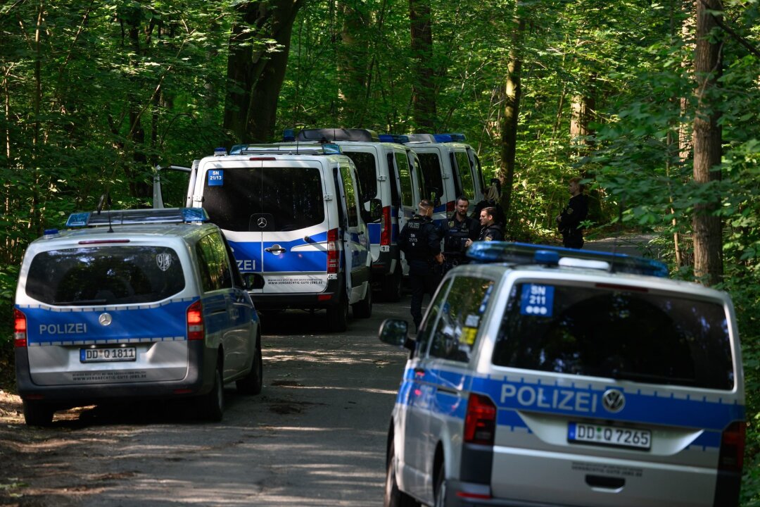"Döbeln ist erschüttert" - Stadtfest am Wochenende abgesagt - Polizisten stehen auf einer Straße in einem Wald. Bei der Suche nach der vermissten neunjährigen Valeriia hat die Polizei im sächsischen Döbeln eine Leiche gefunden.
