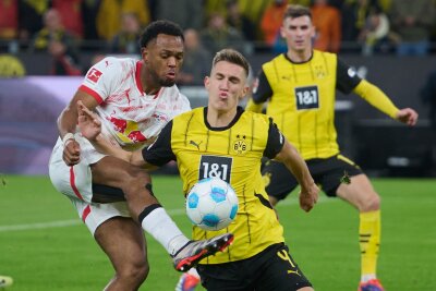 Dortmund schlägt Leipzig - Kiel feiert Premierensieg - Dortmunds Nico Schlotterbeck und Lois Openda (l) von Leipzig kämpfen um den Ball und den Sieg im Topspiel.