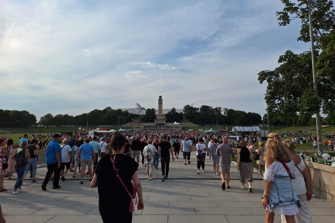 Viele Menschen laufen auf ein Stadion zu.