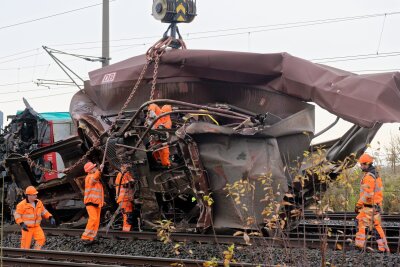 Entgleister Zug bei Köln - Bergung beginnt - Arbeiter befestigen den demolierten Güterwaggon an einem Kran.