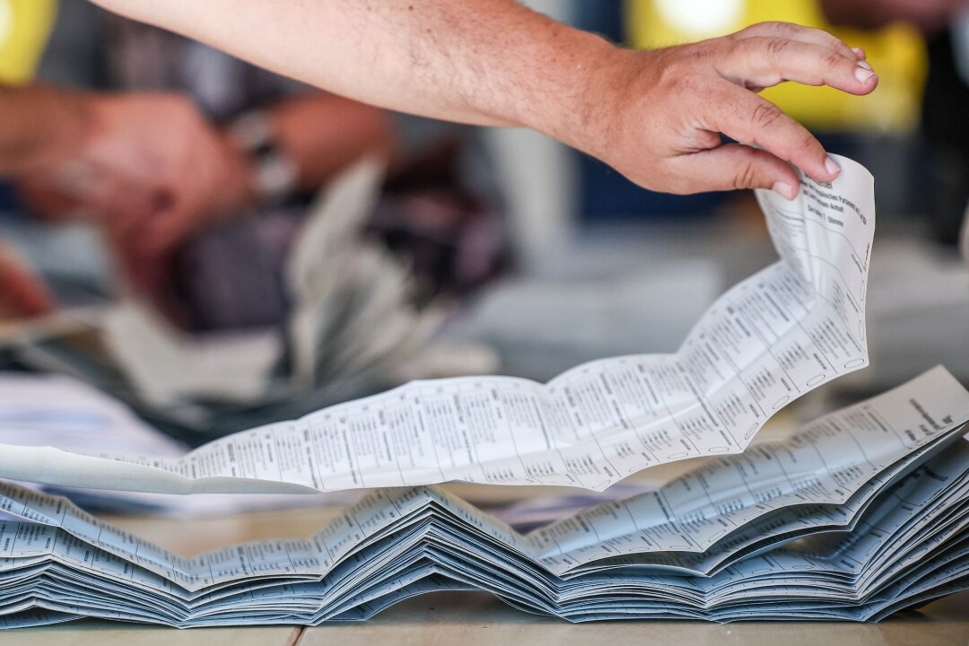 Europa- und Kommunalwahlen: Die Ergebnisse der Region auf einen BLICK - Ein Wahlhelfer legt Stimmzettel zur Stimmenauszählung der Briefwahlstimmen zur Europawahl auf einem Stapel.
