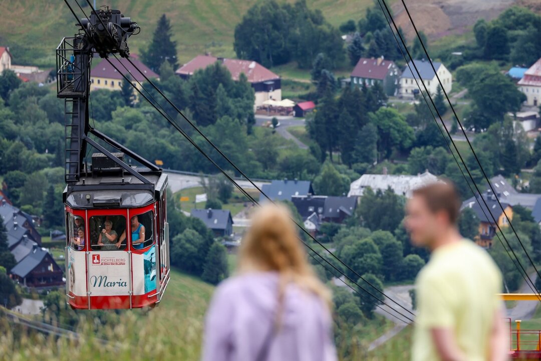 Fichtelberg Schwebebahn wird 100 Jahre alt: Großes Fest - Zwei Spaziergänger beobachten die Ankunft der Fichtelbergschwebebahn an der Bergstation.
