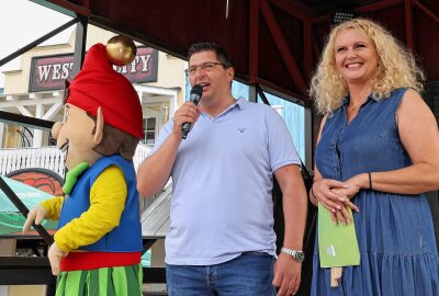 Glücksmomente im Freizeitpark Plohn - Landrat Thomas Hennig (CDU), Silke Fischer und Parkmaskottchen "Plohni" begrüßten auf der Bühne über 300 Gäste aus den Kinder- und Jugendhäusern. . Foto: Thomas Voigt