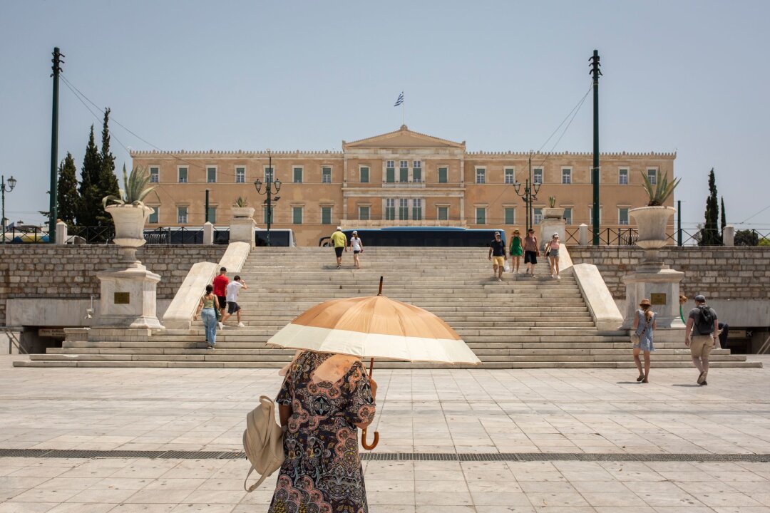 Hitzewelle in Griechenland und der Türkei - Eine Frau schützt sich mit einem Sonnenschirm  auf dem Syntagma-Platz in Athen vor der Sonne: Warme Luftmassen sorgen für Temperaturen von örtlich bis zu 45 Grad.