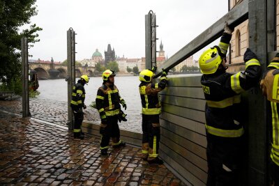 Hochwasser in Europa: Was reiserechtlich gilt - Feuerwehrleute stellen am vergangenen Freitag Teile einer Hochwasserschutzwand in Prag auf. Auch im touristischen Bereich sind die Auswirkungen des Hochwassers spürbar.