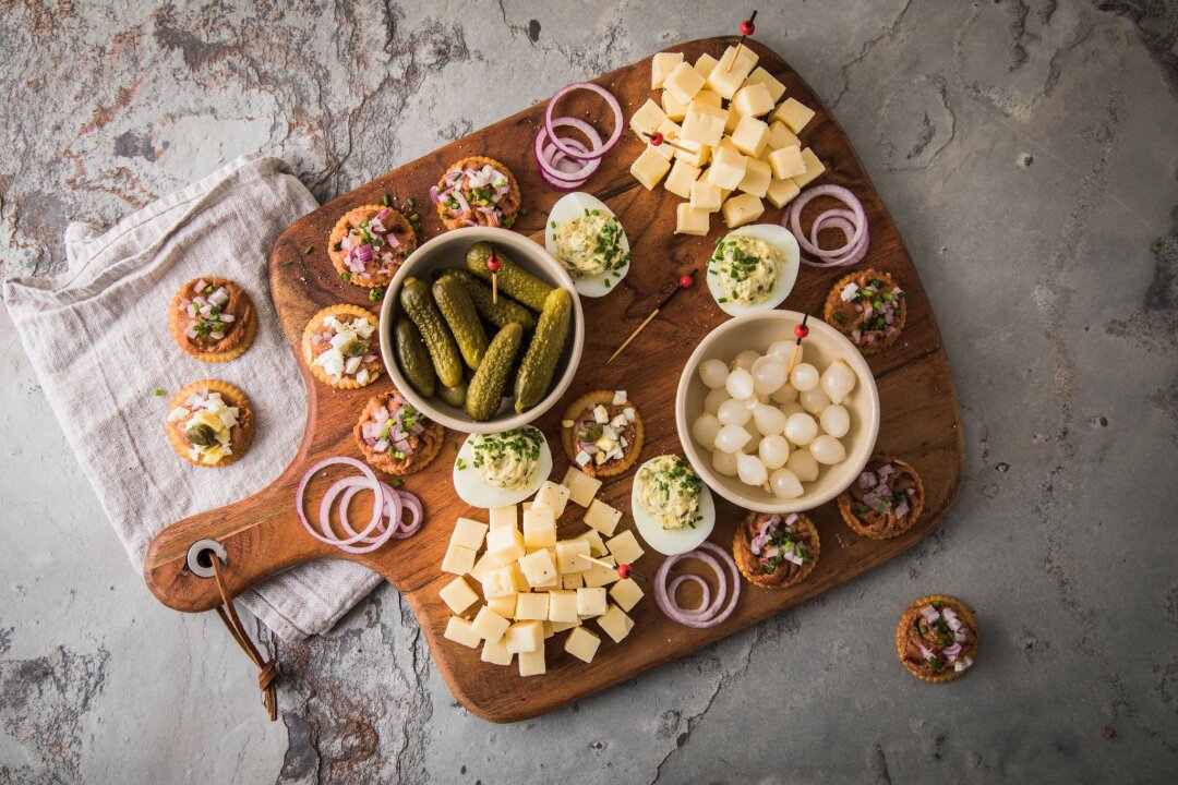 Hollands Antwort aufs Mettbrötchen: Filet Americain - Eine typische niederländische Borrel-Platte mit Filet Americain auf Crackern mit Zwiebel, Ei oder Kapern. Dazu werden Käsewürfel, Cornichons, Silberzwiebeln und gefüllte Eier mit Schnittlauch serviert.