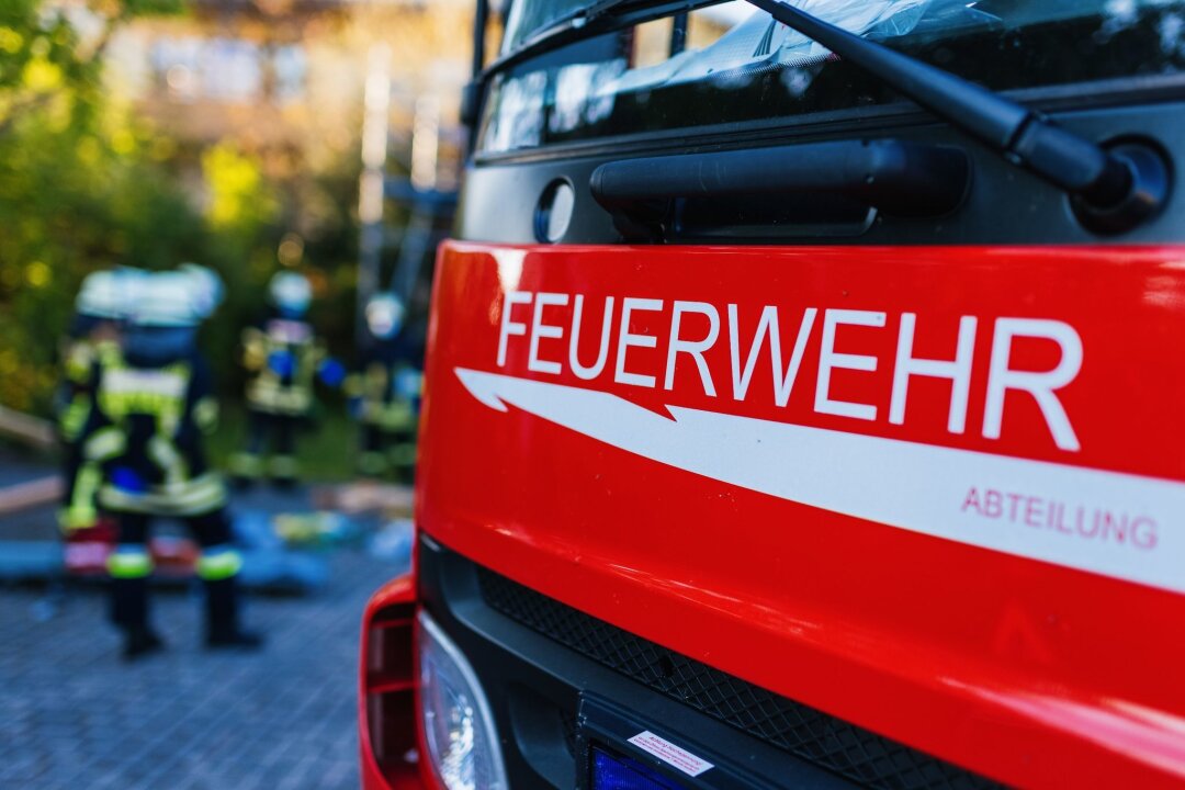 Jugendliche kochen und lösen Wohnungsbrand in Leipzig aus - Feuerwehrleute stehen hinter einem Einsatzfahrzeug.