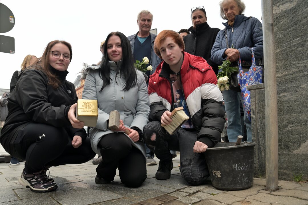 Kleine Gedenktafeln erinnert an Dieter Kreinberg - In Aue ist auf dem Gehweg an der Schwarzenberger Straße 1 ein weiterer Stolperstein verlegt worden, der an Dieter Kreinberg erinnert - im Bild Nathalie Tuchscherer, Anna-Sophie Seifert und Cedric Luber (v.li.) vom IAJ Aue. Foto: Ramona Schwabe    