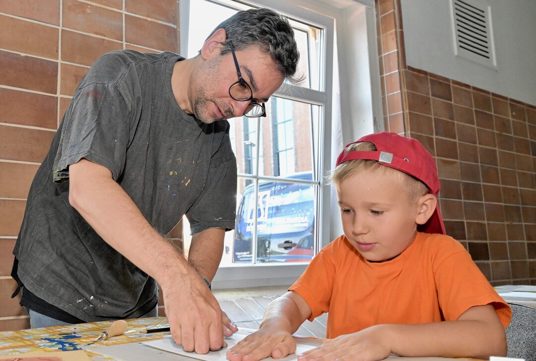 Kreativität gefragt: Hier bekommen Kinder im Erzgebirge künstlerische Techniken vermittelt - Alexander Stoll (li.) hat Kindern, wie Max Wurlitzer (re.), der den Kindergarten "PhoenixONE" in Neuwürschnitz besucht, den Linolschnitt erklärt. Foto: Ralf Wendland