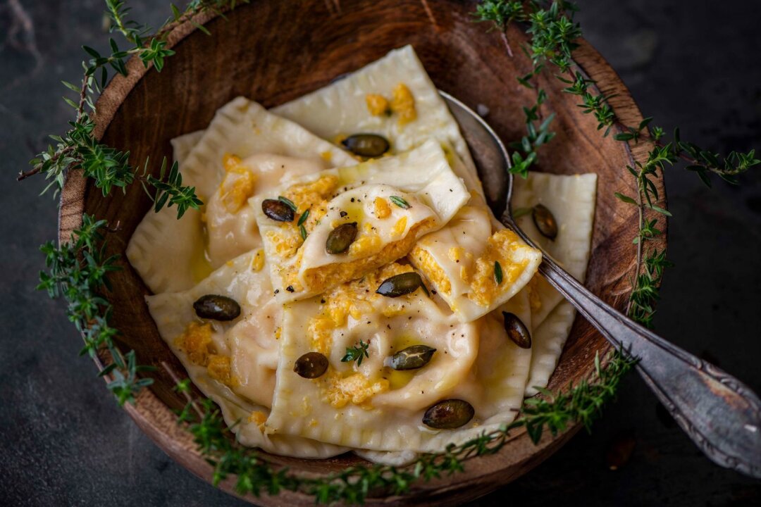 Kürbisravioli mit Orange und gerösteten Kürbiskernen - Einen Teil der Kürbis-Ricotta-Mischung wird zum Servieren über die Ravioli verteilt und mit gerösteten Kürbiskernen und Parmesan getoppt.