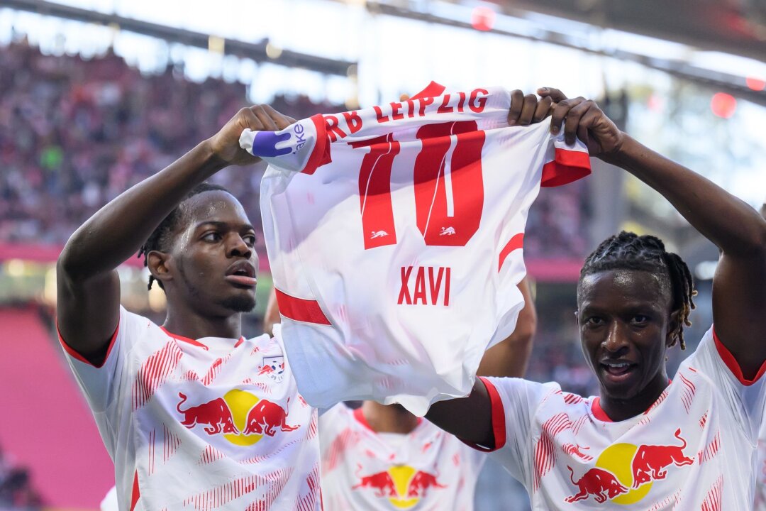 Leipzig bangt nach Freiburg-Sieg um Torhüter Gulacsi - Leipzigs Castello Lukeba (l) und Amadou Haidara halten nach dem 2:1 ein Trikot des verletzten Xavi Simons nach oben.