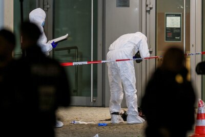 Mutmaßlicher Brandstifter in Krefelder Kino niedergeschossen - Beamte in weißen Schutzanzügen fotografieren blutige Kleidungsstücke und zertrümmerte Glasscheiben.