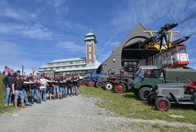 Oldtimer- und Schlepperfreunde waren auf dem Fichtelberg - Die Oldtimer- und Schlepperfreunde aus dem Erzgebirge sind bis auf den Fichtelberg gefahren - dort ein besonders Foto entstanden, das die alte Technik und das Schwebebahn-Jubiläum verbindet. Foto: Ralf Wendland