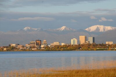 Polarlichter am Highway - Herbstlicher Roadtrip in Alaska - Verschneite Berge im Hintergrund: die Skyline von Anchorage.