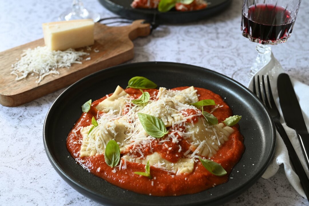 Ravioli in Tomatensoße - mit dem Champi-Parmesan-Trick - Kein Mischmasch: Die selbstgemachten Ravioli thronen beim Servieren auf der Tomatensoße.  Basilikumblätter sorgen für einen Farbtupfer.