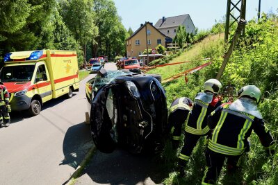 Einsatzkräfte an der Unfallstelle: der PKW liegt nach einem Zusammenstoß mit einer Laterne auf der Seite. Foto: Niko Mutschmann