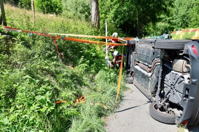 Einsatzkräfte an der Unfallstelle: der PKW liegt nach einem Zusammenstoß mit einer Laterne auf der Seite. Foto: Niko Mutschmann