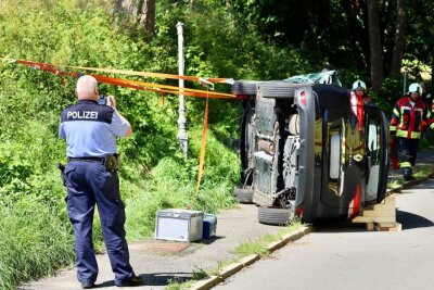 insatzkräfte an der Unfallstelle: der PKW liegt nach einem Zusammenstoß mit einer Laterne auf der Seite.Foto: Niko Mutschmann