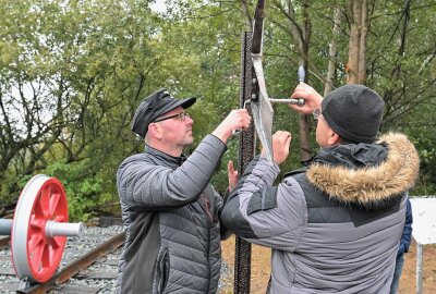 Speicherradsatz bereichert Eisenbahn-Erlebnispfad im Erzgebirge - Mike Robeck (li.) und Jens Hanisch von der IG ZS beim Montieren des Andreaskreuz. Foto: Ramona Schwabe