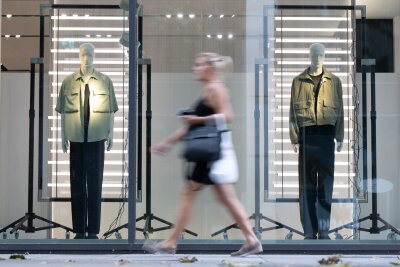 Stimmung in ostdeutscher Wirtschaft leicht gesunken - Eine Passantin gehen in einer Fußgängerzone an einem Schaufenster eines Modegeschäfts vorbei.