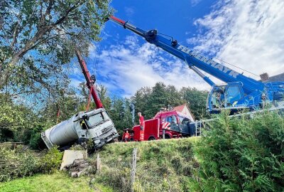 Unfall enger Talstraße in Sachsen: Müllwagen stürzt in Garten - Die Bergungsarbeiten dauern an. Foto: Marko Förster