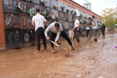 Unwetter in Spanien: Schon mehr als 200 Tote - Männer befreien einen überschwemmten Friedhof am Stadtrand von Valencia von Schlamm.