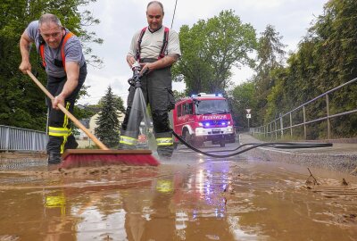 Verschlammte Straßen und mehr: Starkregen überrascht kleine Ortschaften in Mittelsachsen - Zusammen mit den Anwohnendern kämpft die Feuerwehr gegen die Auswirkungen der Unwetterschäden und beseitigt die Schlammlawine. Foto: Bernd März