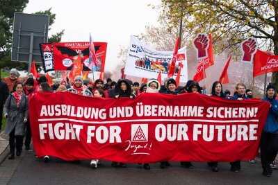 VW-Tarifrunde: Mehr als 6.000 protestieren in Wolfsburg - Auf Transparenten fordern sie den Erhalt aller Standorte und der Übernahmegarantie für Auszubildende.