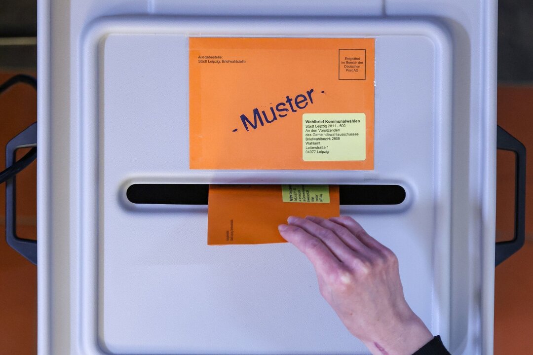 Wahlergebnis herausfordernder für Kommunalparlamente - Eine Frau wirft den Umschlag mit dem Stimmzettel für die Kommunalwahl in eine Wahlurne.